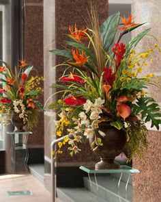 two vases filled with flowers sitting on top of a glass shelf next to a mirror