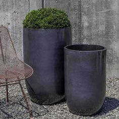 two large black planters sitting next to each other on top of a gravel ground