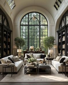 a living room filled with lots of furniture next to large windows and bookshelves