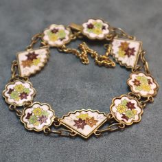 "Wonderful vintage enamel bracelet with flower and fan links. Pretty cloisonne designs on each link of orange, red and green flowers against a white background. It's goldtone metal and has a circular maker's mark on last link. The back of links seem to be textured, or else there's some finish damage, I'm just not sure. The clasp doesn't have any but all other links do. Enamel looks great with no damage. Bracelet measures 7\" long and about 5/8\" wide." Japanese Bracelet, Flower Japanese, Fleur Orange, Enamel Bracelet, Funky Jewelry, Bracelet Vintage, Body Chain Jewelry, Maker's Mark, Dream Jewelry