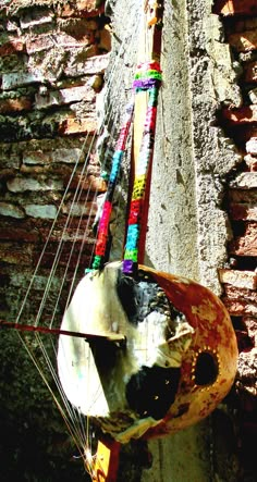 an old boat is hanging on the side of a brick wall with strings attached to it