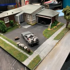 a model car is parked in front of a house with two garages on the other side