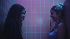 two women standing next to each other in front of a pink tiled wall with headphones on