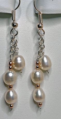 Take three pure white freshwater pearls per earring, attach them to sterling silver chain, and dangle them from French wires. That's the recipe for beautiful earrings that will go with everything. Just for fun, add in a few tiny rose gold beads; that's the finishing touch. These earrings have a 1 1/2 inch drop, and are 2 3/8 inches long overall. Sterling Silver White Pearl Earrings With Pearl Chain, White Sterling Silver Pearl Chain Earrings, Sterling Silver White Pearl Chain Earrings, White Pearl Chain Earrings In Sterling Silver, White Nickel-free Dangle Pearl Earrings, Easy Diy Earrings, Diy Pearl Earrings, Handmade Earings, Pearl Earrings Handmade