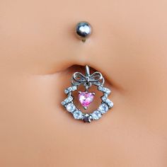 Product DetailsClear Pink CZ Gem Heart Wreath of Love Belly Ring Deck your body with a wreath of love - like this 14 gauge navel ring. It's made with a 3/8 inch 316L surgical grade stainless steel curved barbell with a 5mm top ball end. The bottom end features a festive wreath charm with a bow embellishment at the top and clear cubic zirconia gems all along the bottom. The wreath is further embellished by a dangling pink cubic zirconia gem heart. No matter what the season, why hang a wreath on y Heart-shaped Pink Belly Rings For Gift, Pink Heart-shaped Belly Rings For Gift, Silver Heart Belly Rings For Valentine's Day, Silver Belly Rings For Valentine's Day, Valentine's Day Silver Heart Belly Rings, Adjustable Body Jewelry For Valentine's Day, Cubic Zirconia Belly Rings For Gift, Cubic Zirconia Belly Rings As Gifts, Heart-shaped Silver Body Jewelry For Wedding