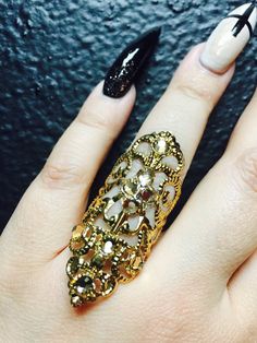 a woman's hand with black and white manicures holding an ornate ring