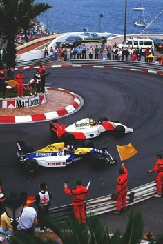 two racing cars on a race track with people watching