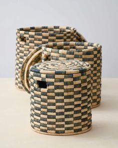 two woven baskets sitting on top of a table next to each other, one with a round lid