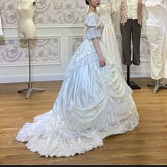 a woman in a white dress standing next to a mannequin