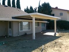 a house with a covered patio in the middle of an empty lot next to it