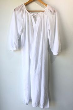 Vintage White Cotton Nightgown. Shirred neckline with small lace trim and tie at notch. Long sleeve also has small lace trim detail. 100% Cotton, machine wash cold. Marked as size M. Approx. Measurements Underarm to Underarm: 25" Length: 44" White Fitted Nightgown For Hospital, Fitted Lace Trim Robe For Spring, Fitted White Nightgown For Hospital, White V-neck Dress, Summer Robe With Lace Trim For Daywear, Fitted Cotton Robe For Daywear, Long Sleeve Lace Trim Nightgown For Summer, Fitted Cotton Nightgown For The Beach, Fitted Peasant Dress For Daywear