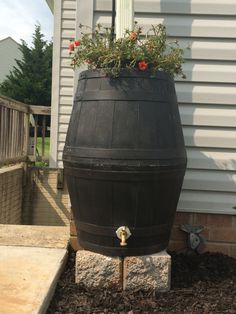 a large wooden barrel with flowers growing out of it in front of a house,