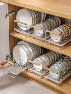 the dish rack is full of dishes and silverware, while someone holds it open