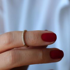 a woman's hand with a red manicured nail polish holding a diamond ring