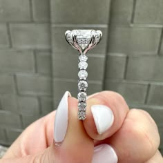 a person holding a diamond ring in their hand with white nail polish on the nails