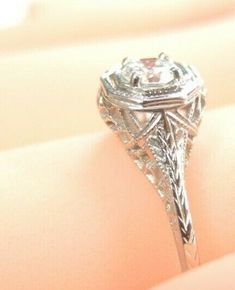 a close up view of a diamond ring on top of a white cloth with an orange background