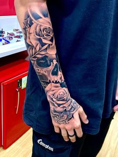 a man with a skull and roses tattoo on his arm is standing in front of a display case