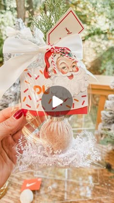 a person holding up a christmas ornament with a santa clause on it's face