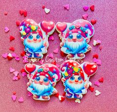 three decorated cookies sitting on top of a pink table