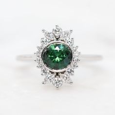 Exquisite Round Gemstones With Halo Setting, Fine Jewelry Diamond Cluster Gemstones, Exquisite Anniversary Gemstones With Halo Setting, Fine Jewelry Emerald With Center Stone, Emerald Cluster Ring With Gemstones, Emerald Cluster Ring With Halo Design, Cluster Diamond Gemstones For Wedding, Green Platinum Halo Ring With Center Stone, Round Cut Platinum Gemstones For Anniversary