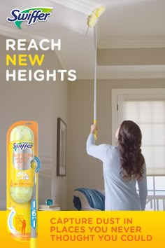 a woman is holding a yellow stick in her hand and cleaning the ceiling with it