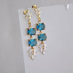 "Montana Blue Earrings // Art Deco Earrings // Statement Earrings // Blue Bridal Earrings // Wedding Earrings // Bridesmaids Earrings // Fan Earrings Beautiful Montana blue earrings created with faceted blue glass and accented with cubic zirconia for added sparkle. These art deco inspired statement earrings are created with gold plated sterling silver earring posts and gold plated butterfly clutches. Whether searching for the perfect blue wedding earrings for your special day or for a pop of color for your next special occasion, all of my jewelry arrives suitably gift wrapped ready for gift giving. Measurements: The length of the art deco earrings hang just under 2\"  Metals: 18k gold plated brass 925 sterling silver plated earring posts These statement earrings are also available in an as Blue Wedding Earrings, Blue Earrings Wedding, Boho Bridal Earrings, Blue Bridal Earrings, Blue Art Deco, Bridesmaids Earrings, Earrings Art Deco, Greenwich Ct, Deco Earrings