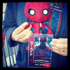 a person holding a spider - man stuffed animal in their right hand and an all access card in his left hand