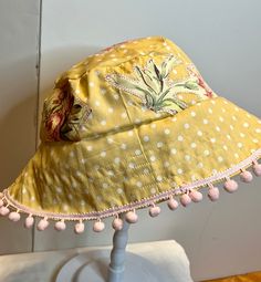 This bucket hat is made from polka dot cotton and patchwork with floral  cutouts that are stitched on.  Great for keeping the sun out in style!    Super cute pastel colors.   The hat measures 22-24 inches.  Embellished with pink ball fringe. Playful Handmade Sun Hat For Summer, Whimsical Brimmed Sun Hat For Summer, Playful Cotton Sun Hat For Vacation, Summer Cotton Hat For Picnic, Playful Summer Sun Hat For Festivals, Summer Cotton Hat For Picnics, Whimsical Adjustable Sun Hat For Summer, Fun Sun Hats For Spring, Handmade Whimsical Sun Hat For Summer