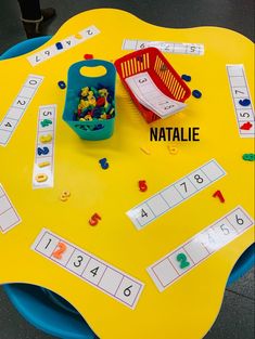 a yellow table topped with lots of toys and numbers on it's surface next to a basket