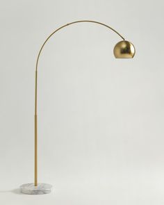 a floor lamp with a marble base and gold colored light bulb on the top, in front of a white background