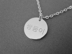 This is a personalized engraved Korean name round pendant sterling silver necklace. The sample necklace is made with the word a twin in Korean in the font style #1. Please check the font options in the pictures. One side or both sides, front & back can be engraved in Korean and numbers. The sample pendant is 15 mm wide. The available 2 pendant sizes are 15 mm and 20 mm. All orders come gift-wrapped. << How to order >> Please choose the engraving side, pendant size and necklace length from the options. Leave the name and font style number you want. The thinner chain is the same chain used in the dainty mini necklace. We'll translate the name for you if you don't know the language. If you don't choose a font, the font used for the sample will be used. The font #2 will be used for numbers if Symbolic Personalized Necklace For Birthday Gift, Silver Jewelry With Engraving Option For Birthday, Sterling Silver Pendant Necklace With Engraved Text, Sterling Silver Necklace With Engraved Text For Anniversary, Silver Jewelry With Engraved Text As Gift, Meaningful Sterling Silver Necklace With Round Pendant, Customizable Sterling Silver Round Disc Necklace, Silver Jewelry With Engraved Text For Gift, Silver Engraved Text Pendant Necklace