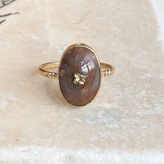 An antique 9 carat gold ring with an Agate  Cabochon stone. This beautiful piece holds a really interesting agate in the centre of a very simple setting, with gold detailing in the middle. The gold going through the Agate is a floral detail and looks really effective. CONDITION: Wear consistent with age and use. Little damage to gold flower. Please see photos for more detail. APPROX. SETTING: 11mm x 16mm SETTING HEIGHT (inc. stone): 5mm APPROX. BAND WIDTH: 2mm RING SIZE: UK: T | US: 9 1/2 WEIGHT: 2.3 grams (VZZ) Heirloom Gold Moonstone Oval Cabochon Ring, Heirloom Gold Moonstone Ring Oval Cabochon, Agate Gemstone Signet Ring For Anniversary, Unique Oval Yellow Gold Moonstone Ring, Unique Yellow Gold Oval Moonstone Ring, Unique Oval Moonstone Ring In Yellow Gold, Oval Yellow Gold Rings With Natural Stones, Victorian Gold Opal Ring Gift, Antique Yellow Gold Oval Cabochon Moonstone Ring