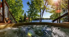 a hot tub with water running down the side and trees in the back ground, on a sunny day