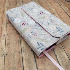 an open notebook on a wooden floor with a pink ribbon around the edge and floral print