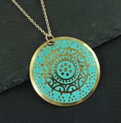 Turquoise and gold medallion necklace features a round gold disc embossed with an ornate design and colored with turquoise enamel. Pendant has a distressed feel with some dark areas on the pendant. This is part of its style. Pendant is 1 3/16 inches in diameter (30mm). Your choice of chain lengths - 16 or 18 inches. Chain is gold plated. Find more necklace styles here - https://www.etsy.com/shop/CharleneSevier?ref=hdr_shop_menu&section_id=10084290 Sign up for my newsletter! Copy and paste this link in your browser - http://eepurl.com/iSq7Wc ---------------------------------- PLEASE READ: This item is not intended for children where choking is a hazard. ---------------------------------- Bohemian Gold Coin Necklace With Round Pendant, Gold Bohemian Coin Necklace With Round Pendant, Blue Etched Round Jewelry, Blue Round Etched Jewelry, Patina Round Pendant Necklaces For Gift, Patina Round Pendant Necklace For Gift, Round Pendant Necklace With Patina For Gift, Turquoise Coin Pendant Jewelry As Gift, Handmade Turquoise Necklace With Round Gold Pendant