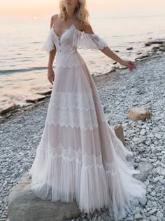 a woman standing on top of a beach next to the ocean wearing a white dress