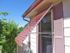 an outside view of a house with shutters on the side and trees in the background