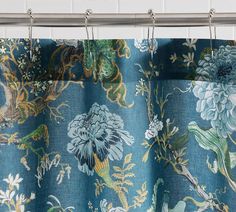 a blue floral curtain hanging from a metal rod