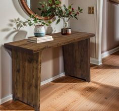 a wooden table sitting in front of a mirror on top of a hard wood floor