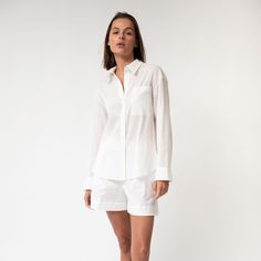 The Linen Voile Signature Shirt is made from premium Linen Voile, featuring a relaxed straight cut with a concealed button placket for a refined and polished appearance. It can be styled with or without a belt and includes a neat collar, yoke, and breast pocket, ensuring both functionality and style.  The crisp white colour provides a clean, bright look for a fresh, modern outfit.  Its semi-transparent nature offers a light and breezy feel, ideal for relaxing at home, casual daytime wear, or bea Timeless Relaxed Fit Shirt For Spring, Spring Daywear Blouse With Concealed Placket, Timeless Relaxed Fit Shirt For Work, Timeless Relaxed Fit Workwear Shirt, Timeless Daywear Blouse With Concealed Placket, Casual Office Blouse With Concealed Placket, Classic Relaxed Fit Blouse For Daywear, Classic Blouse With Relaxed Fit And Spread Collar, Daywear Blouse With Lapel Collar And Concealed Placket