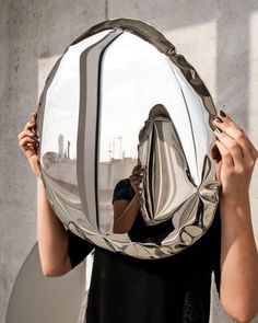 a woman holding up a mirror to her face