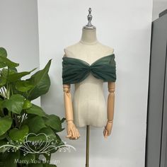 a mannequin with a green bow on it's head next to a potted plant