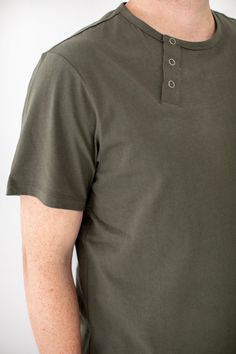 The Essential Everyday Henley Shirt Our core workwear Henley Tee is now available in a new color: Olive. This versatile tee features an apron neck tab and sleeve pocket, making it a practical choice for kitchen and service staff. Customize it with logos to impress, or let its understated silhouette make a statement on its own. Crafted from 100% premium cotton sourced from China, this tee offers substantial quality in the classic new Olive color. Pair it with the Olive Essentials Pants for a cohe Relaxed Fit Button T-shirt For Everyday, Green Short Sleeve T-shirt For Work, Green Polo Collar Top For Work, Green Polo Collar Workwear Tops, Collared Tops For Everyday, Solid Collared Tops For Everyday, Everyday Relaxed Fit T-shirt With Buttons, Everyday Cotton T-shirt With Buttons, Cotton T-shirt With Buttons For Everyday