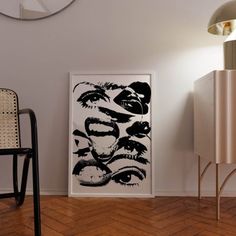 a black and white painting on the wall next to a chair in front of a cabinet