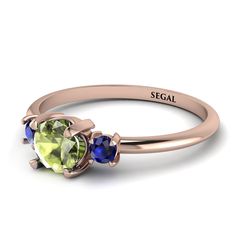 a rose gold ring with two green and blue stones on the side, set in 18k yellow gold