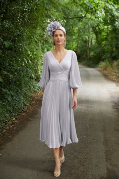 a woman is walking down the road wearing a dress and headpiece with flowers in her hair