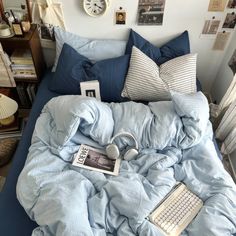 an unmade bed with blue sheets, pillows and headphones on top of it