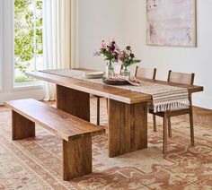 a dining room table with two benches in front of it and flowers on the table