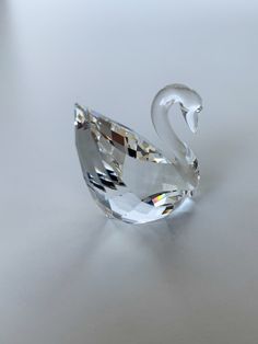 a crystal swan figurine sitting on top of a white table next to a diamond