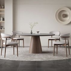 a round table with four chairs and a vase on the wall in front of it